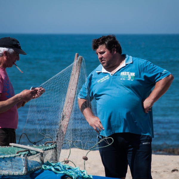 Fishermen mending nets by the sea